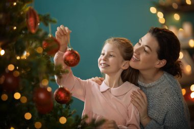 Mutlu Noeller, mutlu tatiller. Anne ve kızı kapalı alanda ağacın yanında. Noel 'den önceki sabah. 