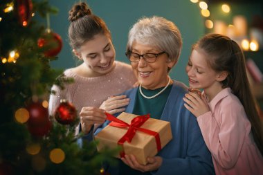 Mutlu Noeller, mutlu tatiller. Büyük anne ve torunlar ağacın yanında hediyeler veriyorlar..