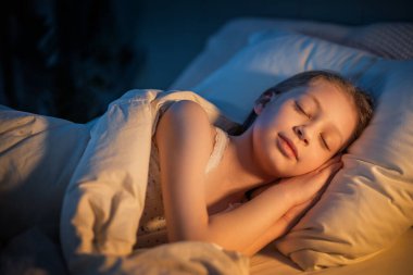 Sevimli küçük kız evdeki yatakta uyuyor..