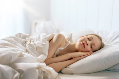 Sevimli küçük kız evdeki yatakta uyuyor..