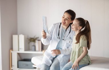 Doktor muayenehanesindeki bir doktoru dinleyen kız hasta..