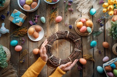Paskalya tatili geçmişi. Ahşap masada renkli yumurtalar ve çiçekler. Üst görünüm