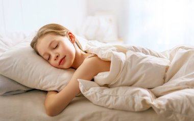 Sevimli küçük kız evdeki yatakta uyuyor..