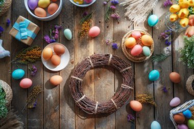 Paskalya tatili geçmişi. Ahşap masada renkli yumurtalar ve çiçekler. Üst görünüm