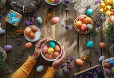 Paskalya tatili geçmişi. Ahşap masada renkli yumurtalar ve çiçekler. Üst görünüm