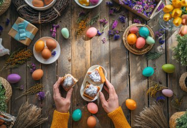 Paskalya tatili geçmişi. Ahşap masada renkli yumurtalar ve çiçekler. Üst görünüm
