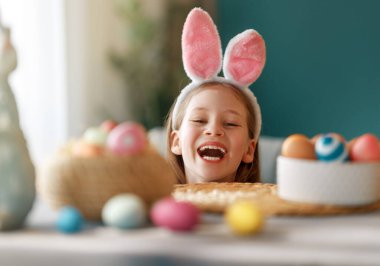 Yumurta boyayan güzel bir çocuk. Mutlu aile Paskalya için hazırlanıyor. Sevimli küçük kız tavşan kulağı takıyor..  