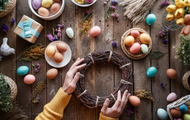 Paskalya tatili geçmişi. Ahşap masada renkli yumurtalar ve çiçekler. Üst görünüm