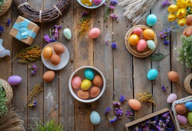 Paskalya tatili geçmişi. Ahşap masada renkli yumurtalar ve çiçekler. Üst görünüm