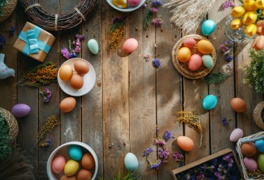 Paskalya tatili geçmişi. Ahşap masada renkli yumurtalar ve çiçekler. Üst görünüm