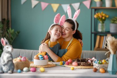 Anne ve kızı yumurta boyuyor. Mutlu aile Paskalya için hazırlanıyor. Tavşan kulağı takan şirin bir kız çocuğu..