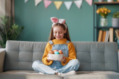 Yumurta boyayan güzel bir çocuk. Mutlu aile Paskalya için hazırlanıyor. Sevimli küçük kız tavşan kulağı takıyor..  