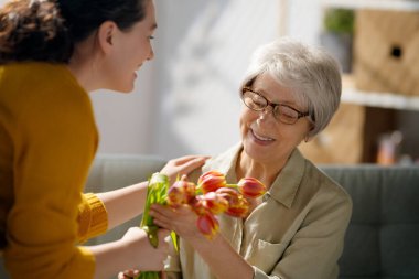 Güzel genç bir kadın ve elinde çiçeklerle annesi ellerinde laleler..  