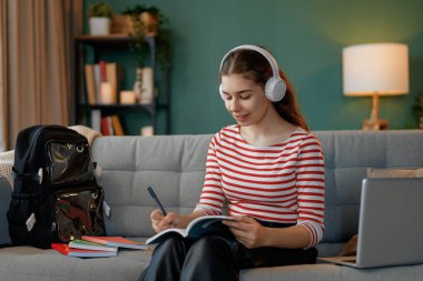 Mutlu çocuk kanepede oturuyor. Genç kız ödevini yapıyor..