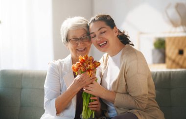 Güzel genç bir kadın ve elinde çiçeklerle annesi ellerinde laleler..  