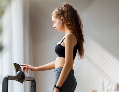 Ev antrenmanı. Koşu bandında koşan genç bir kadın..