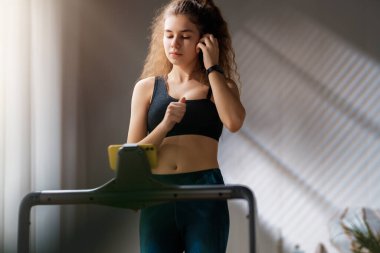 Ev antrenmanı. Koşu bandında koşan genç bir kadın..