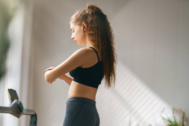 Ev antrenmanı. Koşu bandında koşan genç bir kadın..