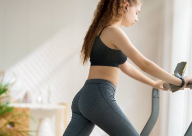 Ev antrenmanı. Koşu bandında koşan genç bir kadın..