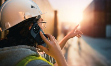 Beyaz şapkalı kadın endüstriyel mühendis konteyner terminalinde çalışıyor..