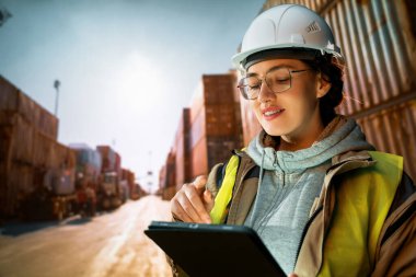 Beyaz şapkalı kadın endüstriyel mühendis konteyner terminalinde çalışıyor..