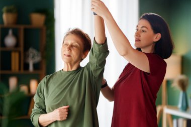 Kıdemli kadın egzersiz yapıyor. Evde fizik tedaviye yardım eden bir hemşire.