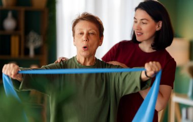 Kıdemli kadın egzersiz yapıyor. Evde fizik tedaviye yardım eden bir hemşire.