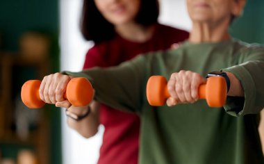 Kıdemli kadın halter egzersizi yapıyor. Evde fizik tedaviye yardım eden bir hemşire.