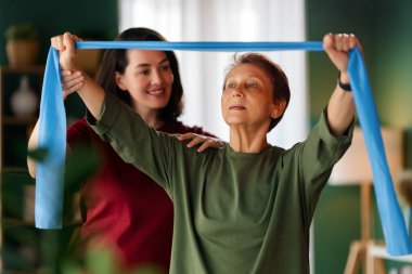 Kıdemli kadın egzersiz yapıyor. Evde fizik tedaviye yardım eden bir hemşire.