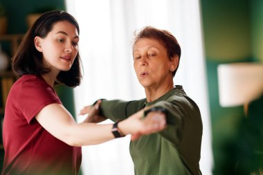 Kıdemli kadın egzersiz yapıyor. Evde fizik tedaviye yardım eden bir hemşire.