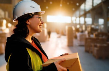 Beyaz şapkalı genç kadın depoda çalışıyor.