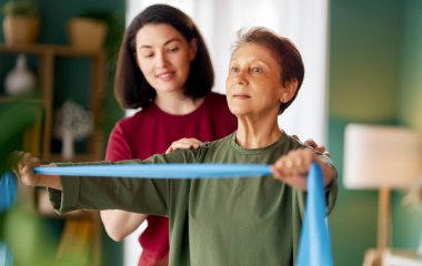 Kıdemli kadın egzersiz yapıyor. Evde fizik tedaviye yardım eden bir hemşire.