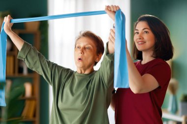 Kıdemli kadın egzersiz yapıyor. Evde fizik tedaviye yardım eden bir hemşire.