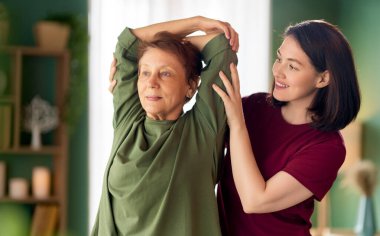 Kıdemli kadın egzersiz yapıyor. Evde fizik tedaviye yardım eden bir hemşire.