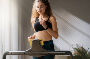 Ev antrenmanı. Koşu bandında koşan genç bir kadın..