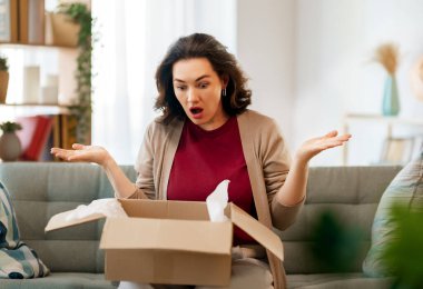 Kadın karton kutuları açıyor. Hayal kırıklığına uğramış online alışveriş kavramı.