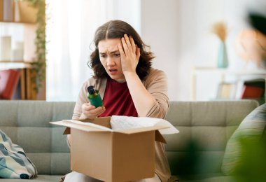 Kadın karton kutuları açıyor. Hayal kırıklığına uğramış online alışveriş kavramı.