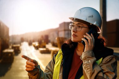 Beyaz şapkalı kadın endüstriyel mühendis konteyner terminalinde çalışıyor..