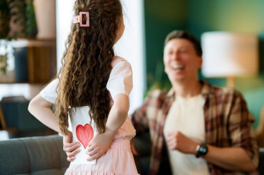 Çocuk kızı babasını tebrik ediyor ve ona kartpostal veriyor. Aile tatili ve birliktelik.