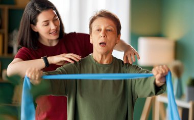 Kıdemli kadın egzersiz yapıyor. Evde fizik tedaviye yardım eden bir hemşire.