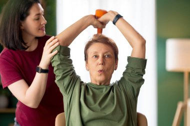 Kıdemli kadın halter egzersizi yapıyor. Evde fizik tedaviye yardım eden bir hemşire.