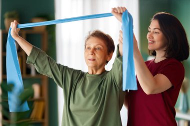 Kıdemli kadın egzersiz yapıyor. Evde fizik tedaviye yardım eden bir hemşire.