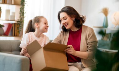 Anne ve kızı karton kutuları boşaltıyorlar. Çevrimiçi alışveriş kavramı.