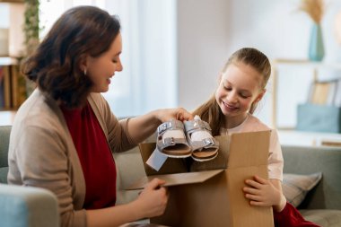 Anne ve kızı karton kutuları boşaltıyorlar. Çevrimiçi alışveriş kavramı.
