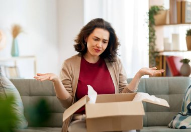 Kadın karton kutuları açıyor. Hayal kırıklığına uğramış online alışveriş kavramı.