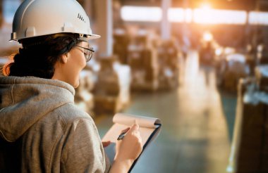 Beyaz şapkalı genç kadın depoda çalışıyor.