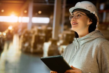 Beyaz şapkalı genç kadın depoda çalışıyor.