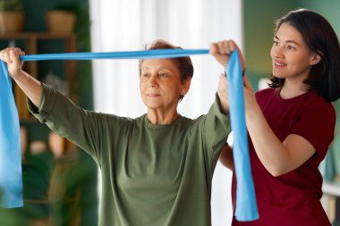 Kıdemli kadın egzersiz yapıyor. Evde fizik tedaviye yardım eden bir hemşire.