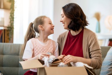 Anne ve kızı karton kutuları boşaltıyorlar. Çevrimiçi alışveriş kavramı.