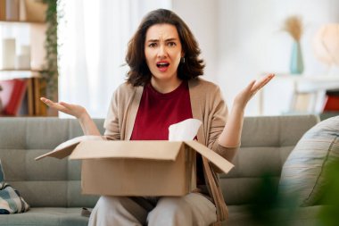 Kadın karton kutuları açıyor. Hayal kırıklığına uğramış online alışveriş kavramı.